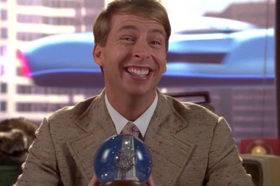 Kenneth Parcell from 30 Rock smiling enthusiastically while holding a snow globe, wearing a beige suit and tie in his NBC office with city views behind him.