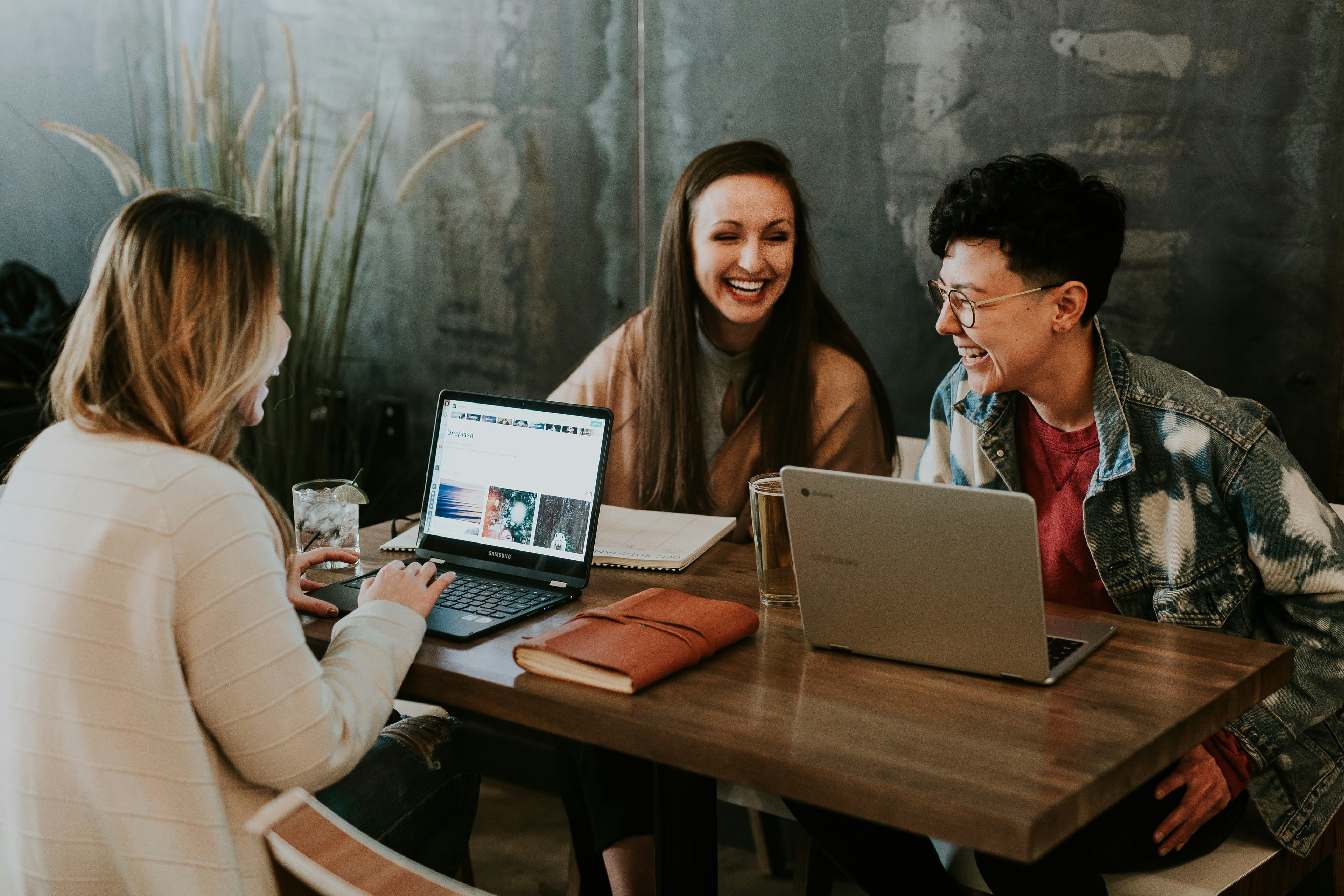 A diverse group of workers sit at a table with laptops